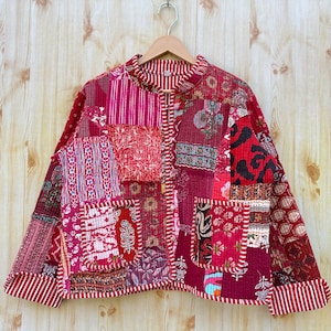 Könnte beinhalten: Eine rote gesteppte Jacke mit Patchwork-Muster. Die Jacke hat einen Stehkragen und einen Knopfverschluss. Der Stoff ist aus Baumwolle und ist weich und bequem.