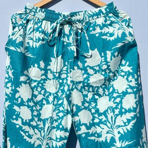 Pu&ograve; includere: Pantaloni blu turchese con motivo floreale bianco. I pantaloni hanno una cintura elastica con coulisse.