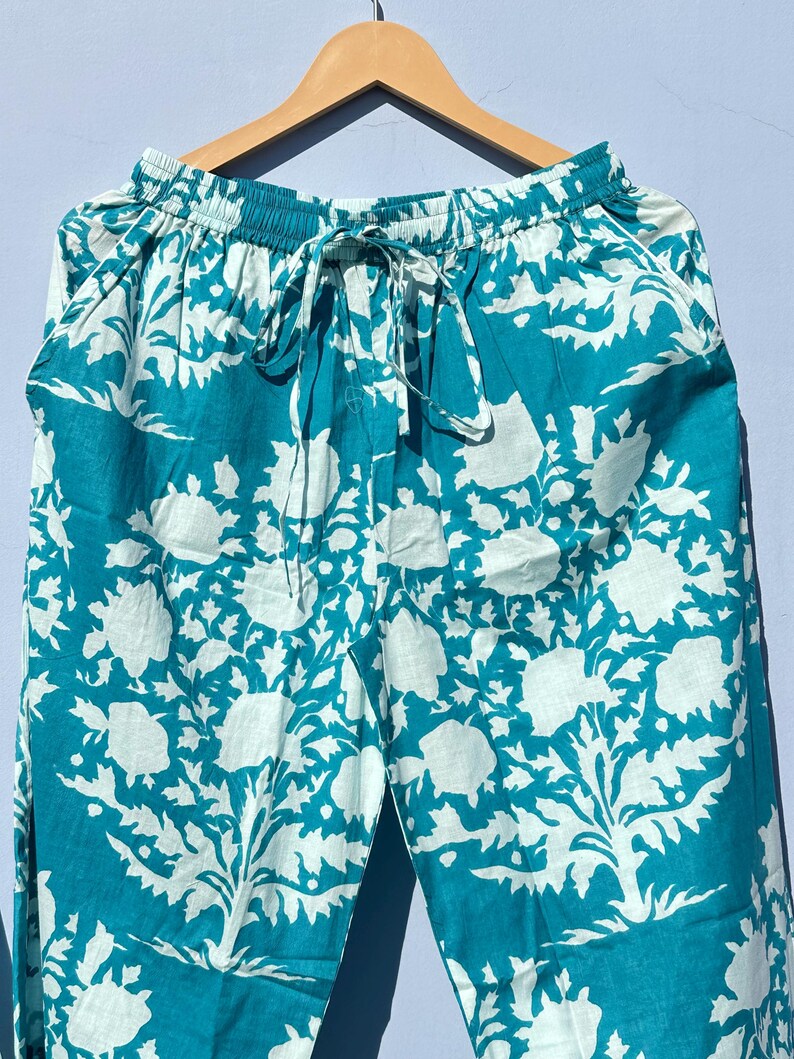 Pu&ograve; includere: Pantaloni blu turchese con motivo floreale bianco. I pantaloni hanno una cintura elastica con coulisse.