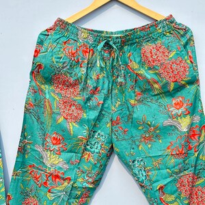 May include: Teal blue pajama pants with a floral and bird print. The pants have an elastic waistband and a drawstring.