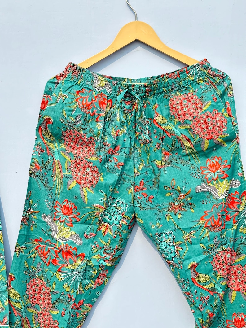 May include: Teal blue pajama pants with a floral and bird print. The pants have an elastic waistband and a drawstring.