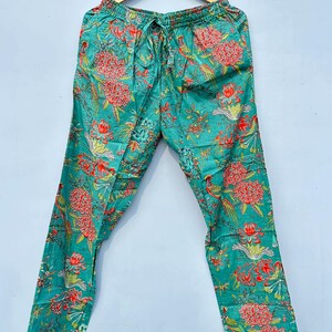 May include: Teal blue pajama pants with a floral print featuring red, pink, and green flowers and birds. The pants have a drawstring waist and white trim.