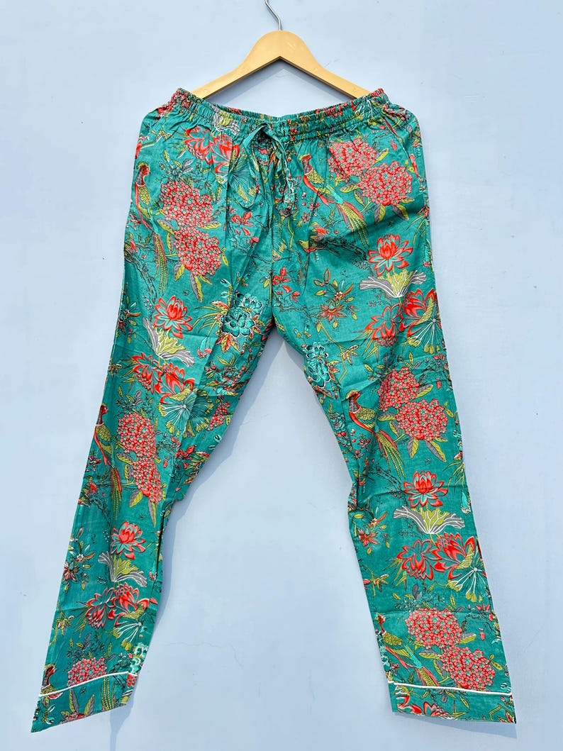 May include: Teal blue pajama pants with a floral print featuring red, pink, and green flowers and birds. The pants have a drawstring waist and white trim.