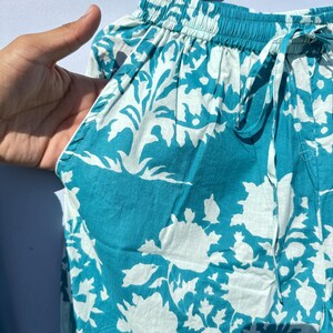 Pu&ograve; includere: Pantaloni da pigiama blu turchese con motivo floreale bianco. I pantaloni hanno un elastico in vita e un cordoncino.