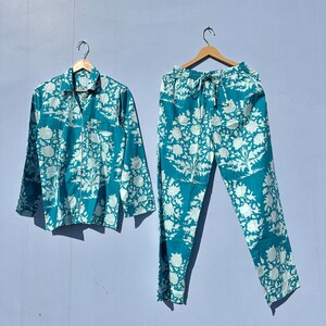 Pu&ograve; includere: Un pigiama blu turchese con stampa floreale bianca. Il set comprende una camicia a maniche lunghe con bottoni e pantaloni abbinati.