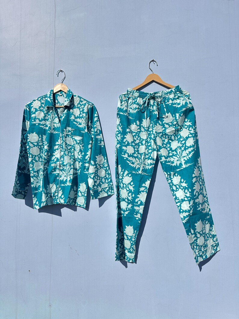 Pu&ograve; includere: Un pigiama blu turchese con stampa floreale bianca. Il set comprende una camicia a maniche lunghe con bottoni e pantaloni abbinati.