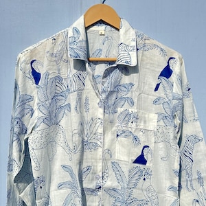 May include: A white long-sleeved button-up shirt with a blue and white tropical print featuring toucans, zebras, leopards, and palm trees.