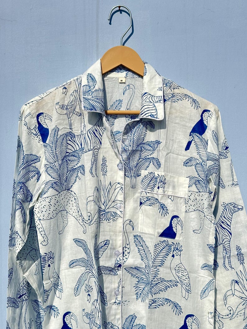May include: A white long-sleeved button-up shirt with a blue and white tropical print featuring toucans, zebras, leopards, and palm trees.