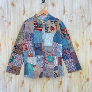May include: A patchwork quilted jacket with a variety of colors and patterns, including blue, green, red, and brown. The jacket has a mandarin collar and a button closure.