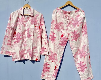 May include: A white pajama set with a pink and red tropical print featuring toucans, palm trees, and leopards. The set includes a long-sleeved shirt and pants.