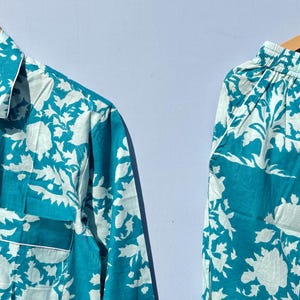 Pu&ograve; includere: Un pigiama blu turchese con un motivo floreale bianco. Il set comprende una camicia a maniche lunghe con bottoni e pantaloni abbinati.