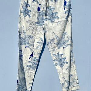 May include: White trousers with a blue and white tropical print featuring toucans, flamingos, and leopards.
