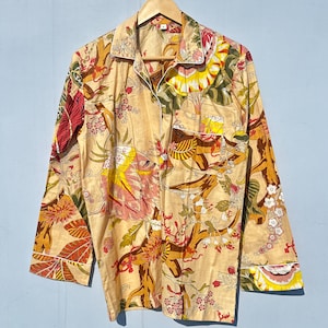 Op de afbeelding: Een lang mouw overhemd met een bloemenprint in tinten geel, oranje, rood en groen. Het overhemd heeft een knoopsluiting aan de voorkant en een zak op de linker borst.