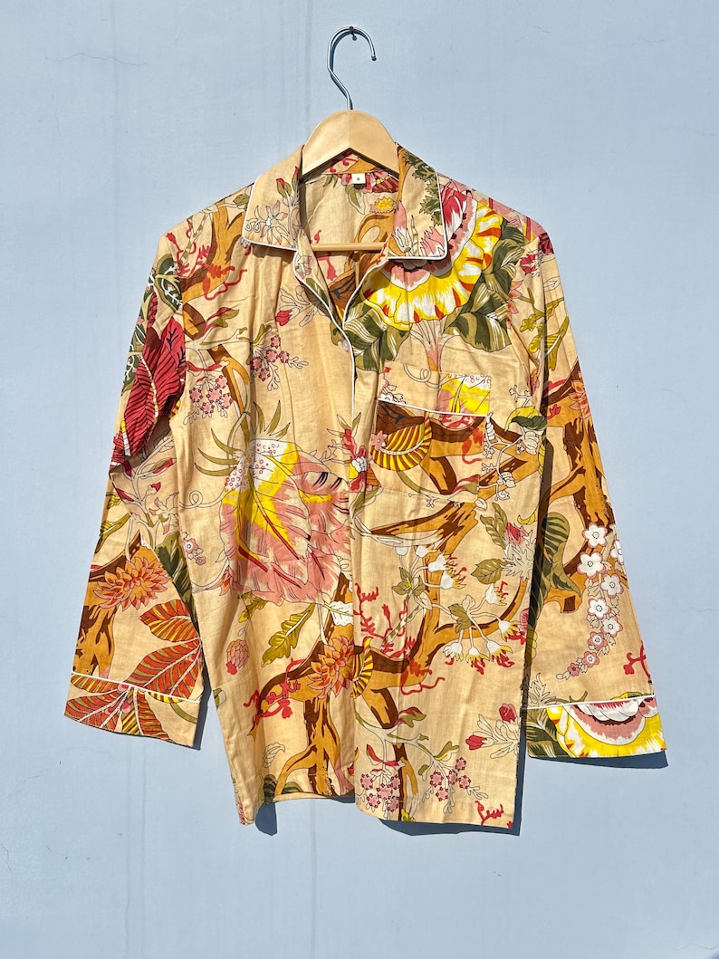 Op de afbeelding: Een lang mouw overhemd met een bloemenprint in tinten geel, oranje, rood en groen. Het overhemd heeft een knoopsluiting aan de voorkant en een zak op de linker borst.