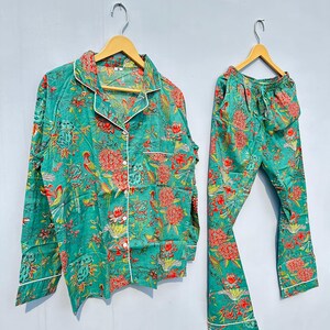 May include: A teal blue pajama set with a floral and bird print. The top has a button-up front and long sleeves. The pants have an elastic waistband.