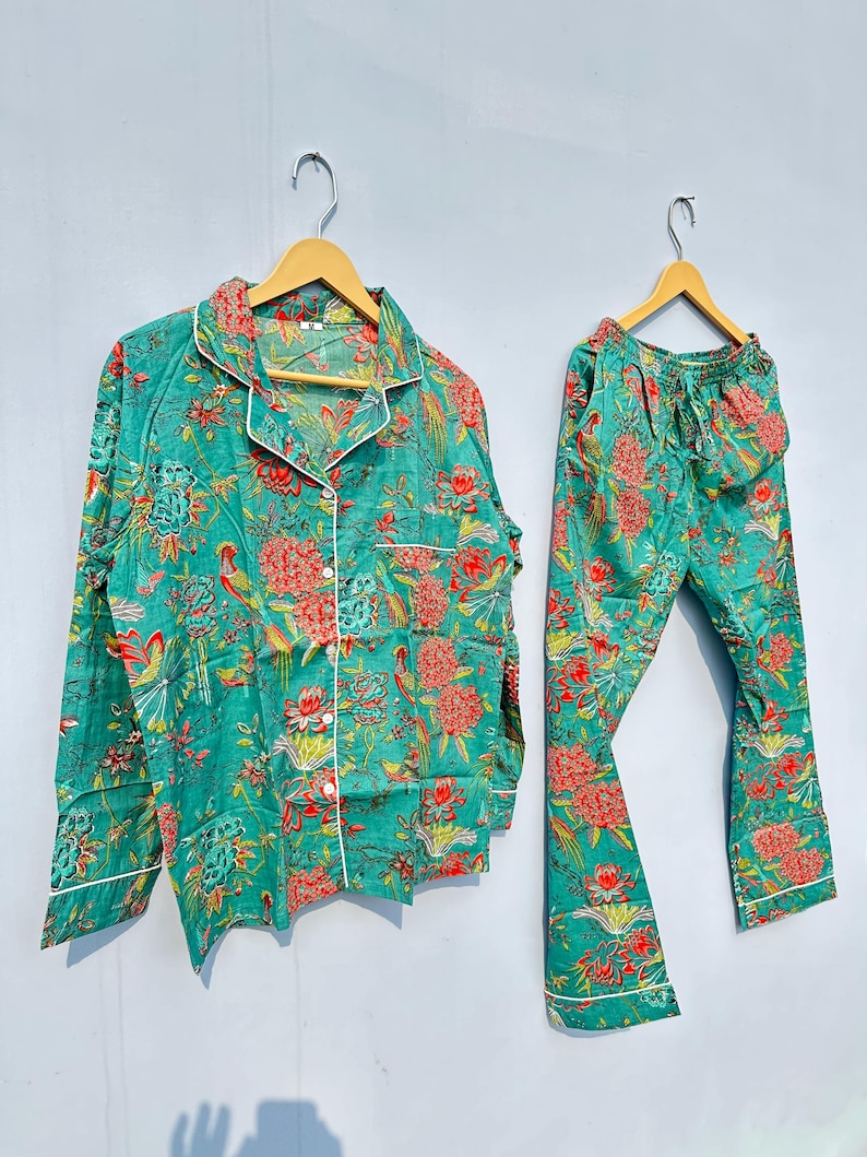 May include: A teal blue pajama set with a floral and bird print. The top has a button-up front and long sleeves. The pants have an elastic waistband.