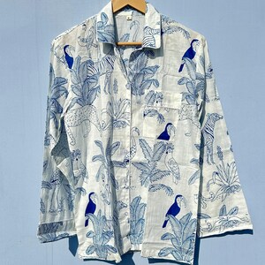 May include: A white long-sleeved button-up shirt with a blue and white tropical print featuring toucans, zebras, and palm trees.