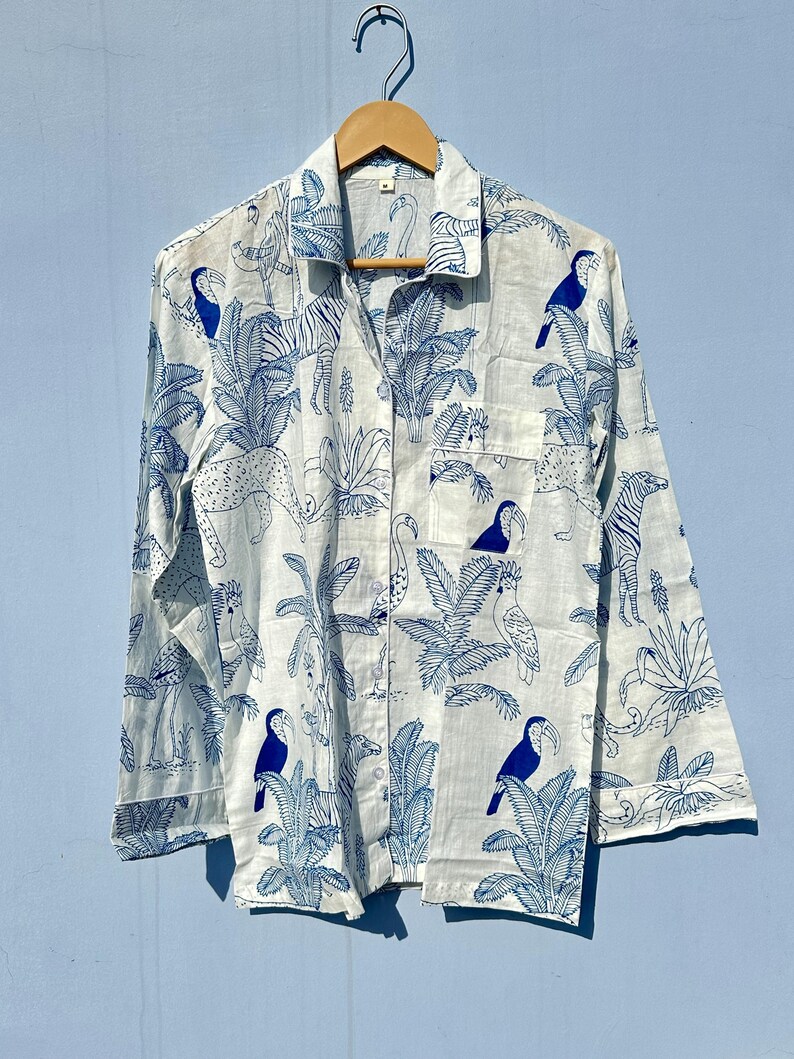 May include: A white long-sleeved button-up shirt with a blue and white tropical print featuring toucans, zebras, and palm trees.