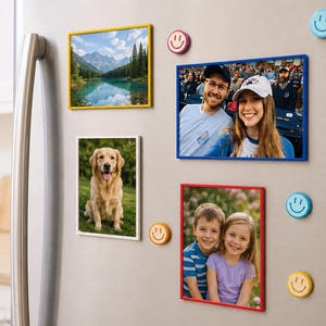 May include: Four rectangular magnetic photo frames in yellow, blue, white, and red, displayed on a metallic surface. The frames hold various photographs, accompanied by five small, round, colorful smiley face magnets in blue, yellow, and pink.