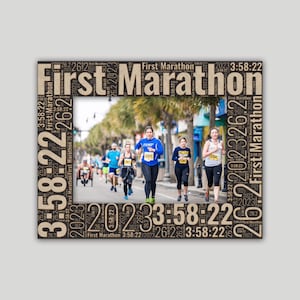 May include: A brown wood frame with a word cloud of "First Marathon" and the time "3:58:22" surrounding a photo of runners in a marathon.