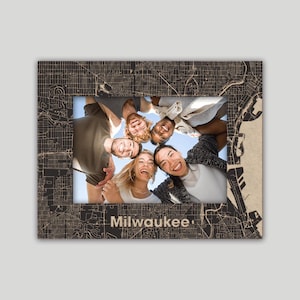 May include: A framed photo of a group of friends smiling and looking at the camera. The frame is made of wood and has a map of Milwaukee, Wisconsin printed on it. The text "Milwaukee" is printed below the photo.