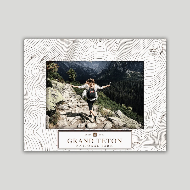 May include: A white and brown topographic map design with a photo of a person hiking in a mountain landscape. The text "ESTD 1929 GRAND TETON NATIONAL PARK" is in brown text on a white background.