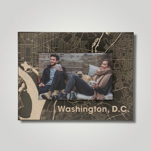 May include: A wooden picture frame with a map of Washington, D.C. printed on the front. The frame has a photo of a couple and their dog inside.