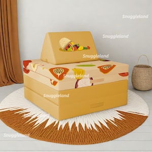 May include: A yellow and white patterned foam play couch with a triangular backrest. The couch is on a round, white and brown rug. The couch has a fruit pattern with papaya, passion fruit, and limes.