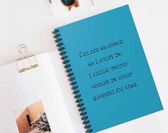 Puede incluir: Una libreta espiral azul con la cita "No soy tan malo como podría ser. Creo que la gente debería estar más agradecida por eso." impresa en negro.