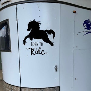 May include: A white horse trailer with a black silhouette of a horse and the text "Born to Ride" on the side.