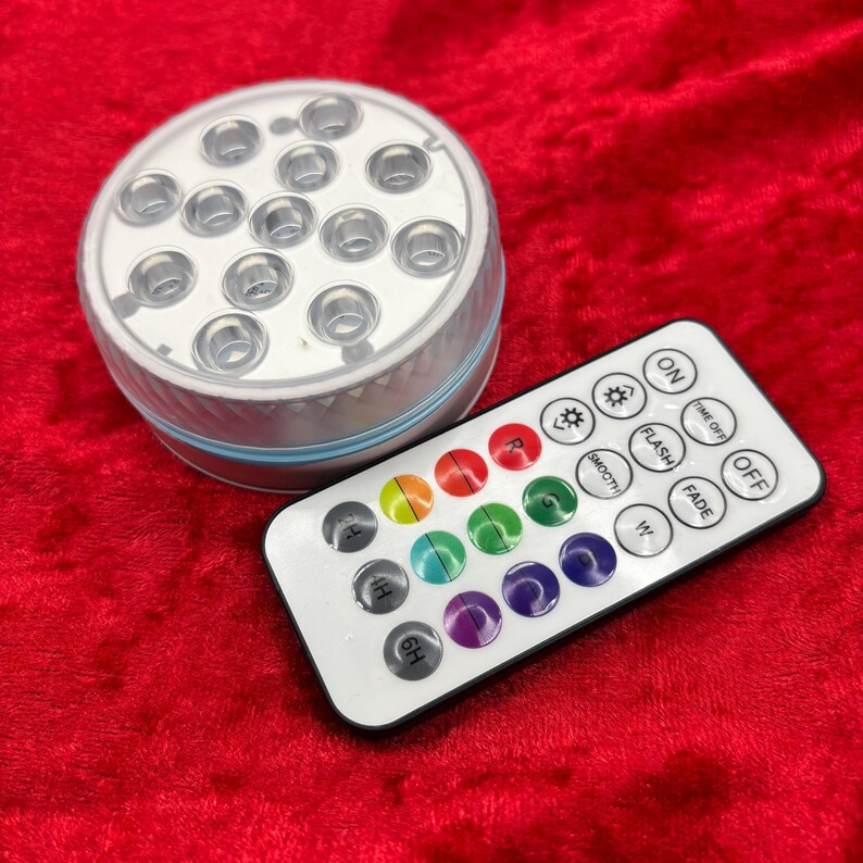 May include: A white round waterproof LED light with 16 lights and a remote control. The remote has buttons for on, off, flash, fade, smooth, and color selection.