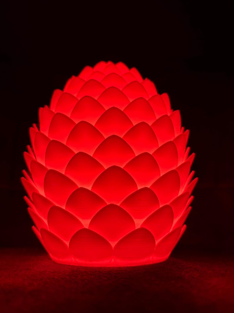 May include: A red, round, decorative lamp shaped like a pinecone with a textured surface.