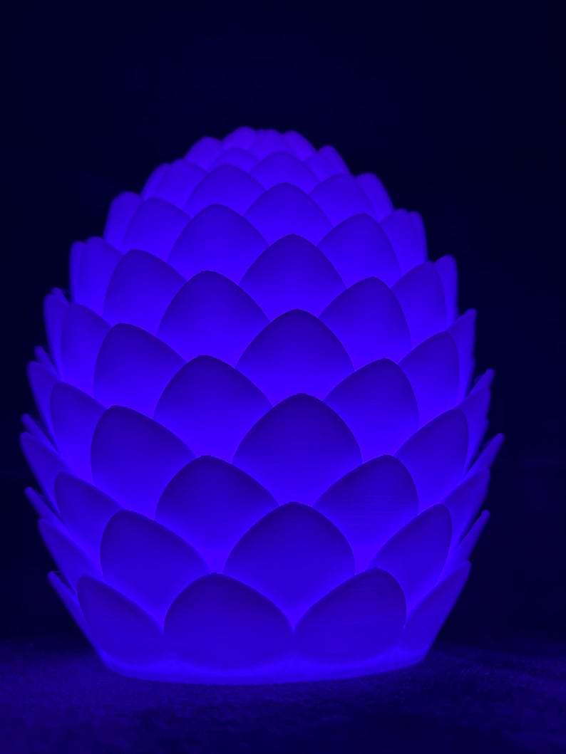May include: A white, ceramic pine cone shaped nightlight with a blue glow.