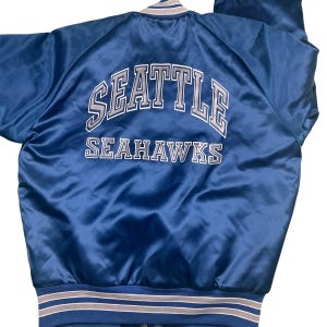 Vintage Seattle Seahawks NFL Chalk Line 80s satin bomber jacket. Quilted lining. Full snap enclosure. Tagged as a youth 14/16,