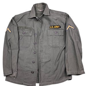 Vintage US Army issue military button front shirt. Early 1960s. Tagged as a small. 21 inches pit a pit, 27 inches long.