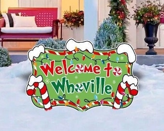 May include: A festive Christmas sign with the words "Welcome to Whoville" in green and red lettering. The sign is decorated with candy canes, lights, and a red and white peppermint swirl.
