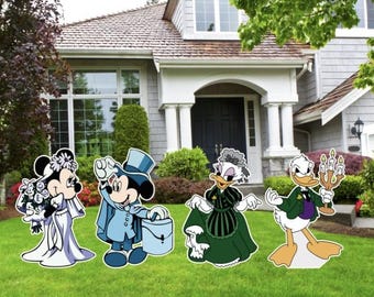 Könnte beinhalten: Vier Comicfiguren stehen auf einem grasbewachsenen Rasen vor einem Haus. Mickey Mouse ist in einem blauen Anzug und Zylinder gekleidet, Minnie Mouse trägt ein weißes Hochzeitskleid, Donald Duck trägt einen grünen Anzug und hält einen Kandelaber, und Daisy Duck trägt ein grünes Kleid.