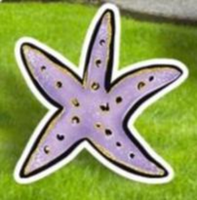 May include: A purple starfish sticker with a black outline and gold accents. The sticker has a white border and is set against a green background, suggesting an outdoor or beach theme. The starfish has five points and small, dark spots.