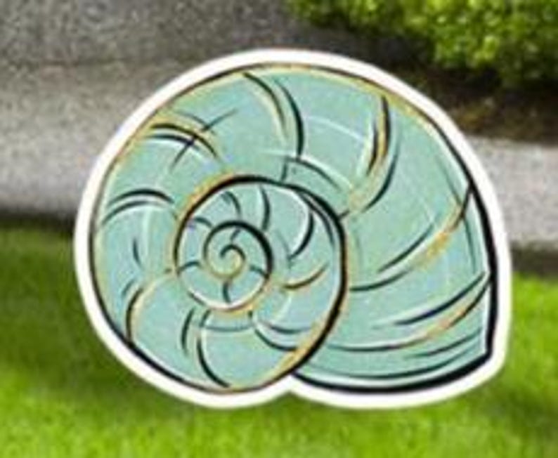 May include: A light blue, spiral-shaped seashell design with black and gold accents. The seashell is outlined in white and sits on a green grassy surface. The design is likely for a garden or home decor.