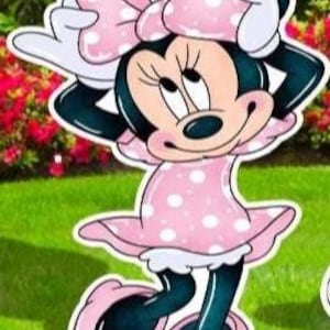 May include: A cutout of Minnie Mouse, featuring a pink polka-dot dress and bow. The character has black ears, a black nose, and white gloves. The cutout is standing on a green lawn with red flowers in the background.