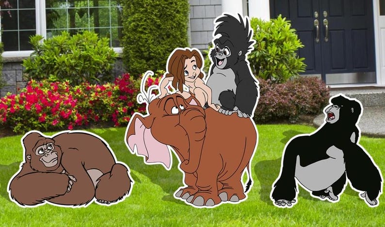 May include: A set of five cartoon character cutouts featuring a brown elephant, a brown gorilla, a black gorilla, a black gorilla, and a girl with brown hair. The cutouts are on a green lawn in front of a house.