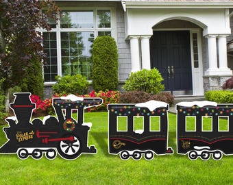 May include: Black silhouette of a train from the movie "The Polar Express" with snow on top and Christmas lights. The train is made of wood and is a yard decoration.