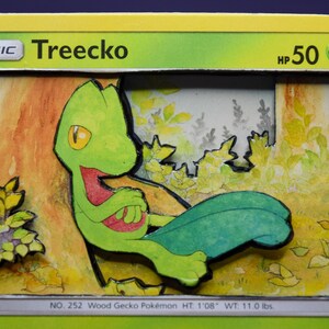 May include: A 3D layered paper art card featuring the Pokémon Treecko. The card displays the text Basic Treecko HP 50, No. 252 Wood Gecko Pokémon HT 1'08 WT 11.0 lbs. The green character is positioned against a painted forest background.