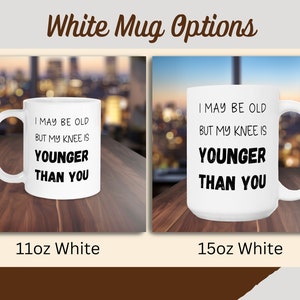 Puede incluir: Dos tazas blancas con un dise&ntilde;o negro que dice "Puedo ser viejo, pero mi rodilla es m&aacute;s joven que t&uacute;". La taza de la izquierda es de 11oz y la taza de la derecha es de 15oz.