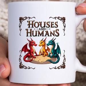 May include: White ceramic mug featuring a colorful illustration of three dragons in red, yellow, and teal. The mug has the text "HOUSES AND HUMANS" in a decorative frame. The dragons are sitting on a map.