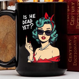 May include: Black coffee mug with a white graphic of a woman with green hair and sunglasses. The text on the mug reads "Is he dead yet?"