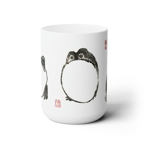 May include: White ceramic mug with black ink drawings of frogs. The frogs are in different poses, including one that is a circle. The mug has a red stamp on the side.