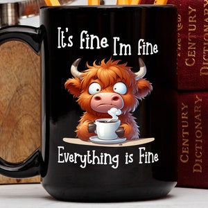 Puede incluir: Taza de café negra con una vaca de las tierras altas de dibujos animados sosteniendo una taza de café. La taza tiene el texto "It's fine I'm fine Everything is Fine" impreso en ella.
