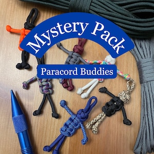May include: A variety of colorful paracord buddies, small figures made from paracord, with the text "Mystery Pack Paracord Buddies" on a blue background.