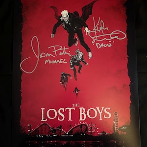May include: A red poster for the movie "The Lost Boys" featuring the main characters in flight. The poster is signed by the actors, including Corey Feldman, Jamison Newlander, and Kiefer Sutherland. The text on the poster reads "Sleep all day. Party all night. Never grow old. Never die. It's fun to be a vampire."